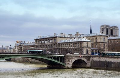 Arch bridge over river against buildings in city