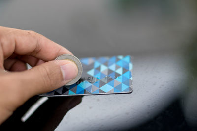 Cropped hand holding coin on credit card