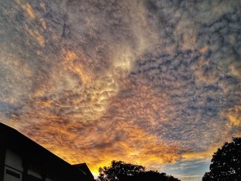 Low angle view of dramatic sky over silhouette trees