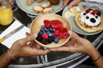 Cropped image of couple holding bowl of fruits