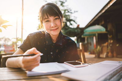 Portrait of a smiling young woman sitting on table