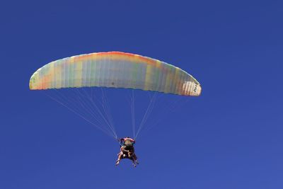 Low angle view of person paragliding against clear blue sky