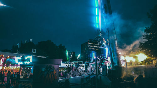 People on illuminated city against sky at night