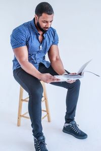 Young man looking away while sitting on wall