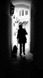 Rear view of silhouette people walking in alley amidst buildings