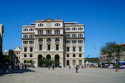 Group of people in front of building against blue sky