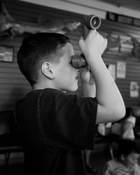 Boy looking through periscope in classroom