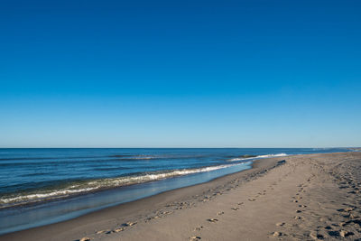 Scenic view of beach against clear blue sky