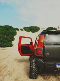 Close-up of red car on land against sky