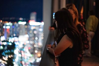 Side view of woman standing on street at night