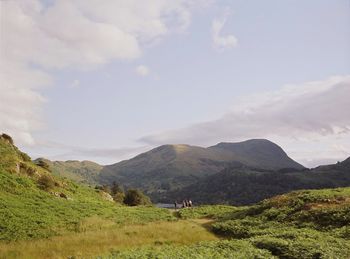 Scenic view of figures hiking on mountains against sky