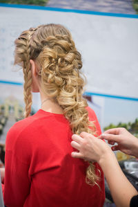 Close-up of female hairstylist holding blond customers hair at salon