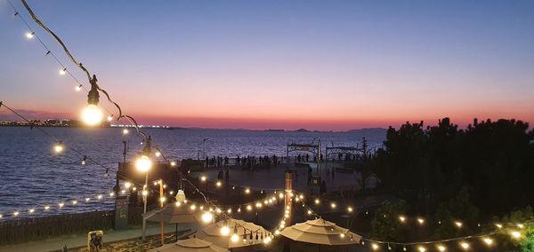 Panoramic view of illuminated city against sky at sunset