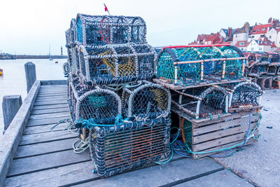 Fishing net on pier at harbor against sky