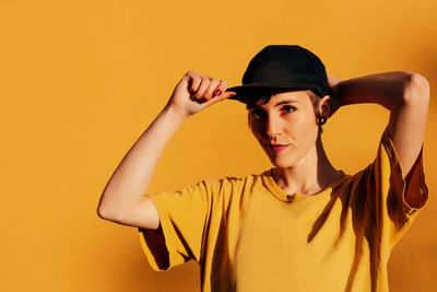 Portrait of young woman against yellow wall