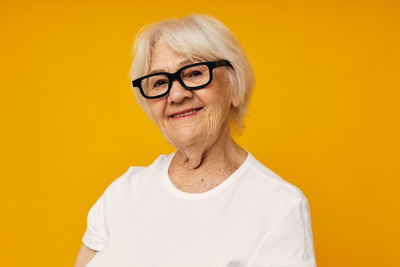 Senior woman smiling against yellow background