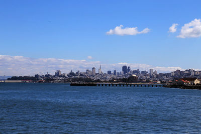 City at waterfront against blue sky