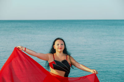 Portrait of woman sitting on sea against sky