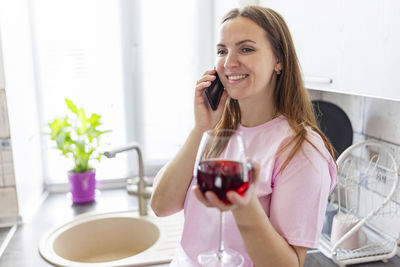 Portrait of young woman holding wineglass while sitting at home