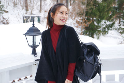 Portrait of smiling young woman standing in snow