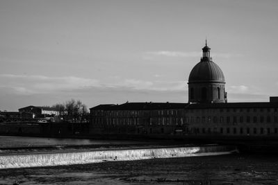 View of building by canal against sky in city