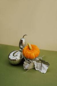 Modern still life with various pumpkins decorated in silver on a podium made of bricks