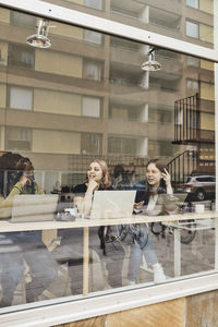 Young female business colleagues discussing with each other while sitting in tech start-up office