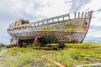 Abandoned boat on beach against sky