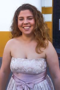 Portrait of smiling young woman in dress standing outdoors