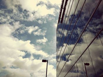 Low angle view of power lines against cloudy sky