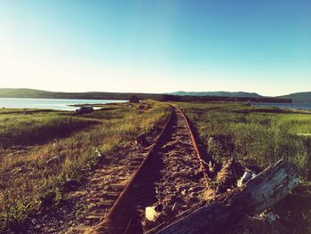 Railroad tracks on field against clear sky