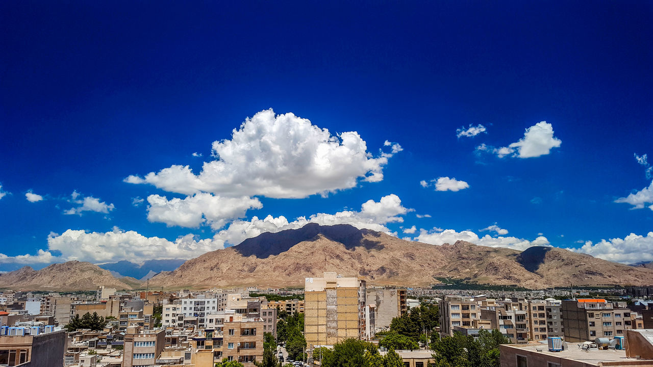 sky, architecture, built structure, building exterior, cloud - sky, blue, building, city, mountain, no people, nature, residential district, day, beauty in nature, town, outdoors, scenics - nature, plant, cityscape, sunlight, townscape