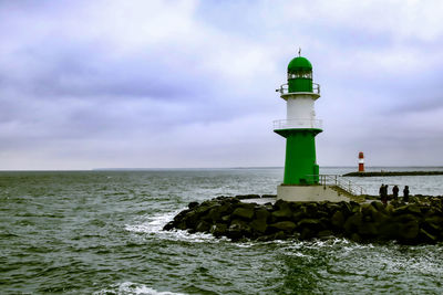 Lighthouse by sea against sky