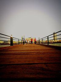 People on footbridge against clear sky