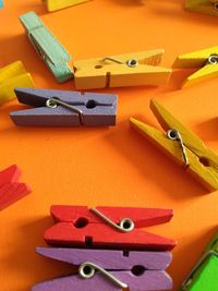 High angle view of colorful wooden clothespins on orange background