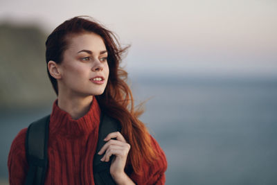 Portrait of beautiful young woman standing against sea