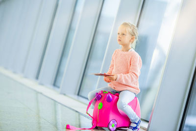 Cute girl sitting on luggage at airport
