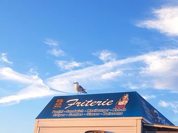 Low angle view of sign against blue sky