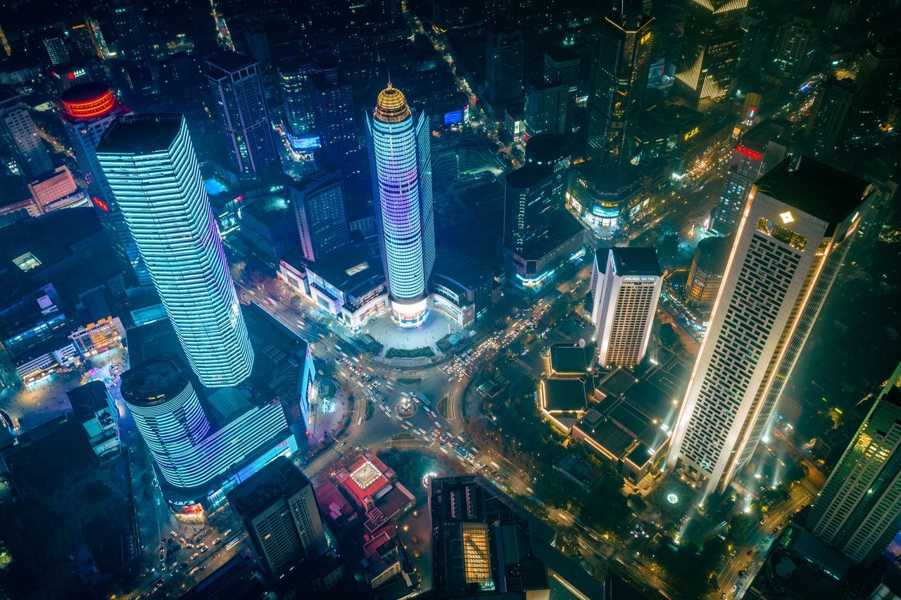 HIGH ANGLE VIEW OF ILLUMINATED MODERN BUILDINGS IN CITY AT NIGHT