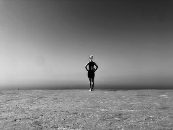 Rear view of woman standing at beach against sky