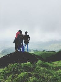 Rear view of men standing on landscape against sky