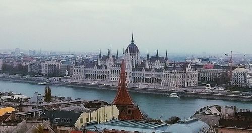 Panoramic view of buildings by river against sky in city