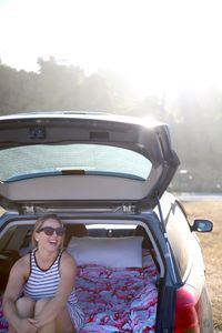 Smiling woman sitting in car trunk