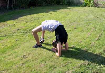 Teenage girl doing acrobatic exercises on a green lawn, sport, generation z,