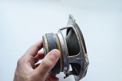 Close-up of hand holding metal against white background