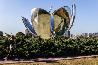 Rear view of man standing by tree against sky