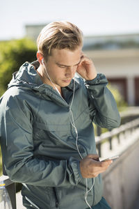 Fit man listening music through mobile phone on bridge