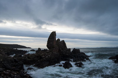 Rock formation on beach against sky