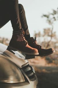 Low section of woman on car against sky