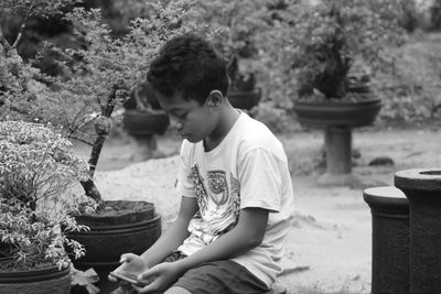 Boy using smart phone while sitting outdoors